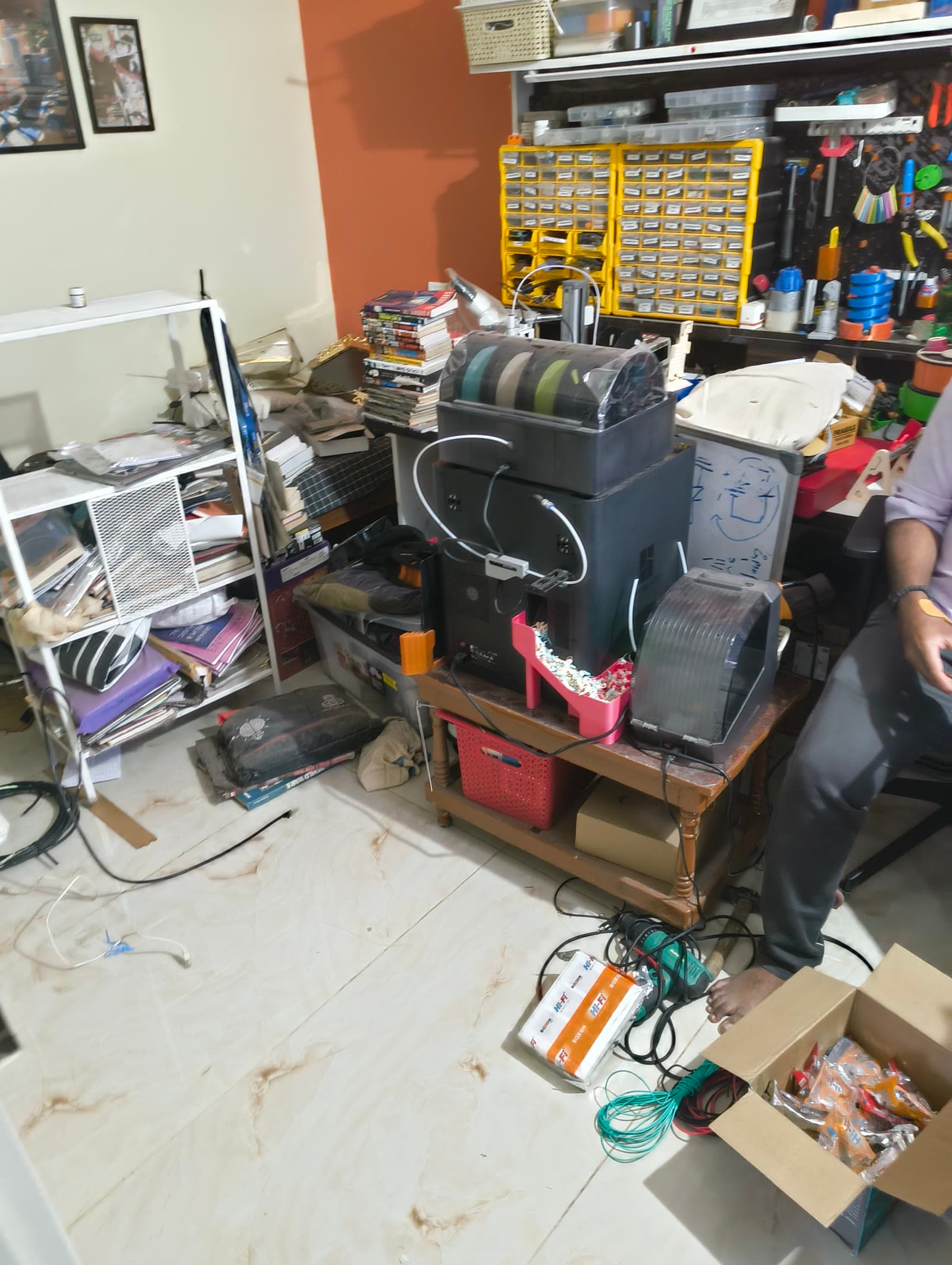 The June 2026 workspace with printers, storage, cables, books, and open boxes