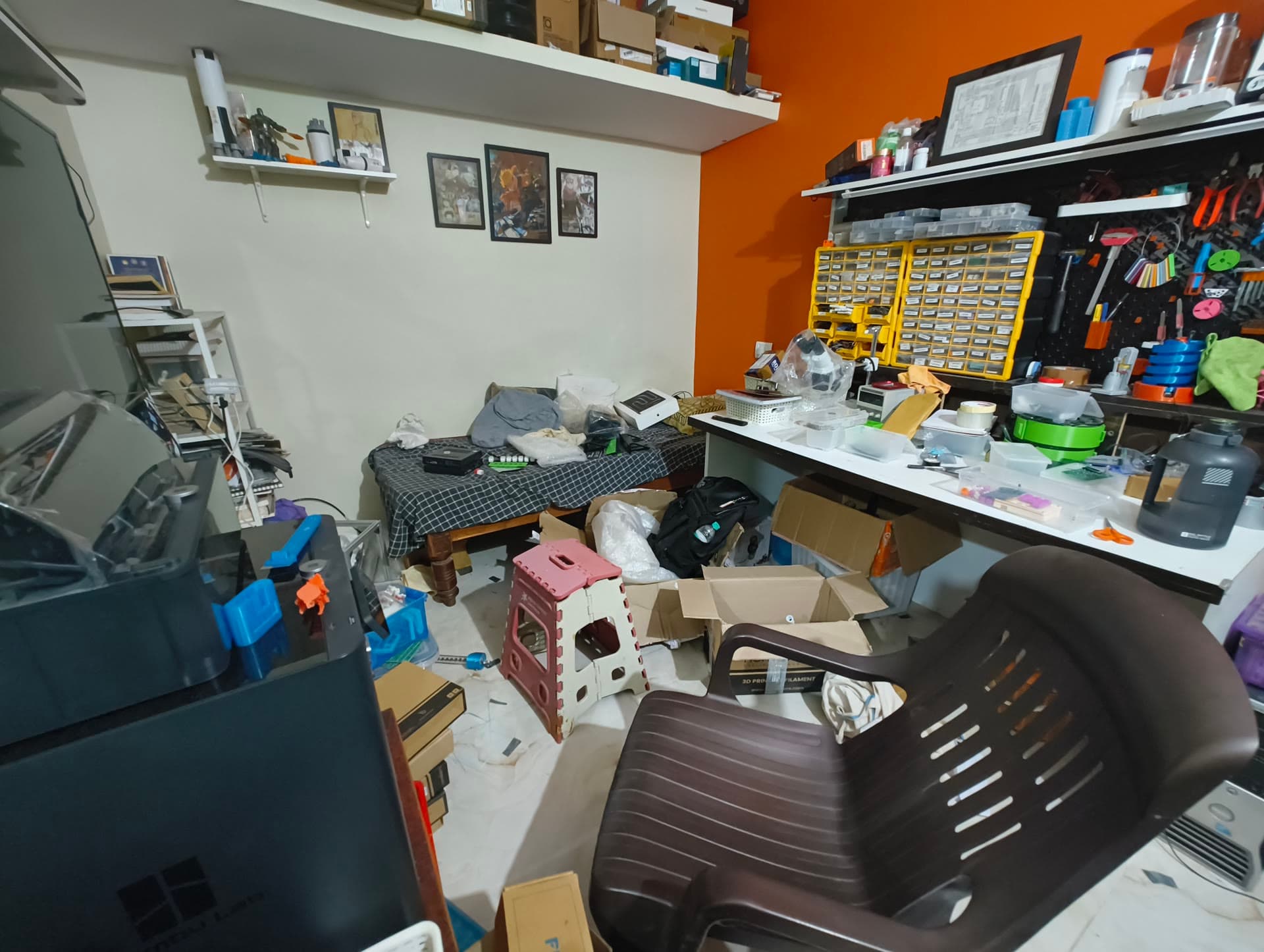 The early workshop crowded with a workbench, storage drawers, tools, boxes, and a single chair