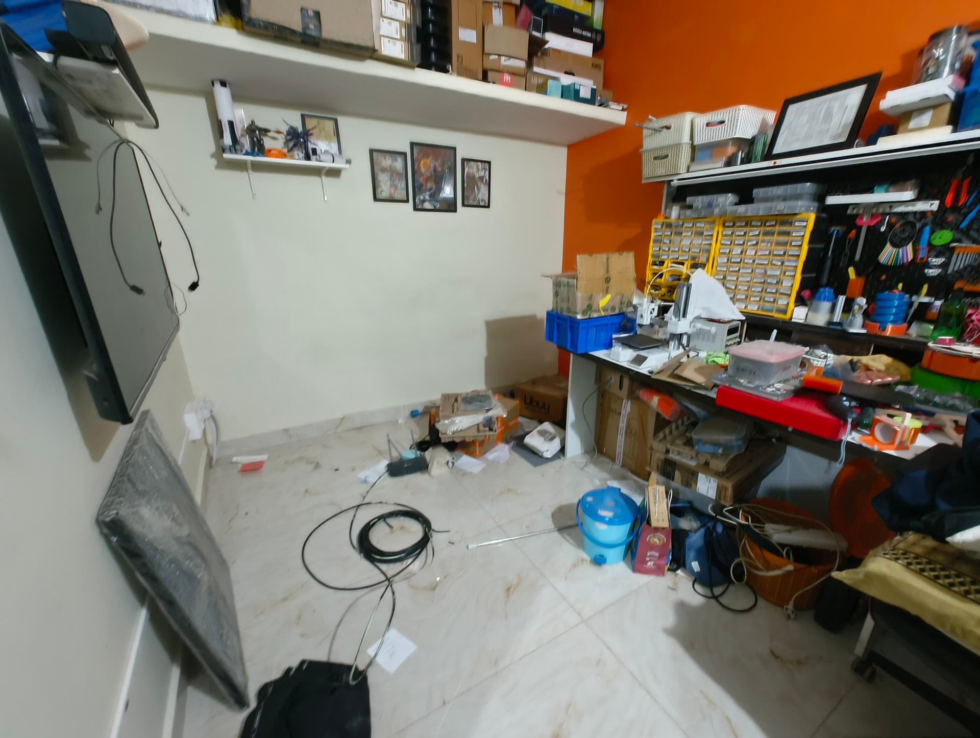 A wide view of the workshop in June 2026 with tools, storage, boxes, and cables filling the room